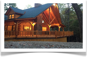 tall trees surronding two story lodge with 4 windows, wrap around deck