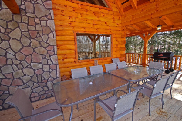 Closeup view of the two deck tables and 10 chairs. Charcoal Grill on right, toward woods