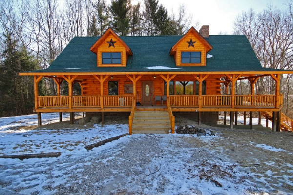 Lodge, front view with steps leading to Wrap-Around Main Deck. Woods behind lodge. Stairway from West side of Porch going down to Fire Pit area