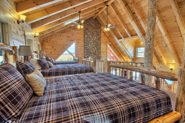 Closeup view across tops of the three Log Queen Beds in open loft, with matching pillows and comforters