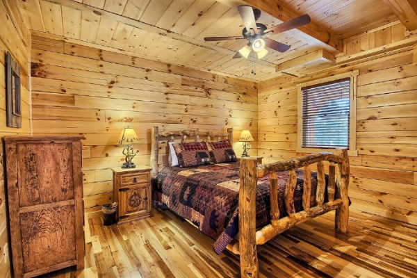 Bedroom 3, on Main Level, with Log Queen Bed, Dresser, Night Stand with Lamps, Window, Hardwood Flooring and Ceiling Fan