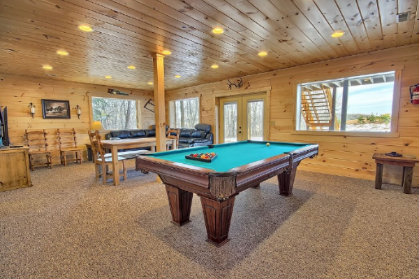 Wide View of Pool Table and same room furniture, with the Walkout Door and large Picture Windows. Carpet Flooring