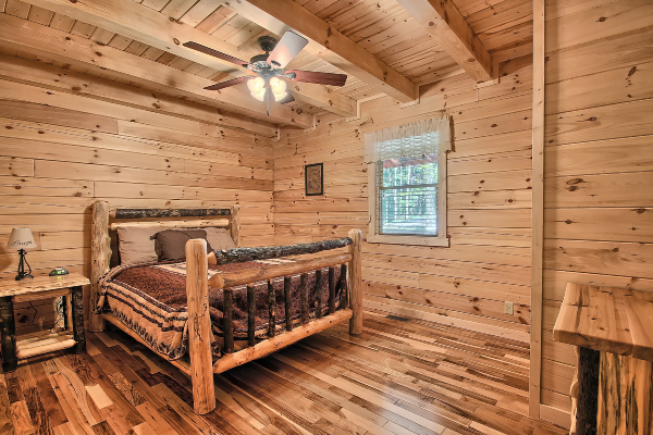 Private Bedroom 3, on Main Floor, with Log Queen Bed, Log Nightstand with lamp, and Log Dresser, Hardwood Flooring, Window and Ceiling Fan