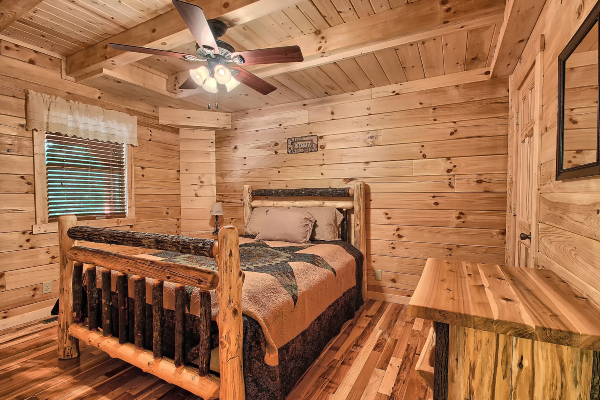 Private Bedroom 4, on Main Floor, with Log Queen Bed, Log Nightstand with lamp, and Log Dresser, Hardwood Flooring, Window and Ceiling Fan