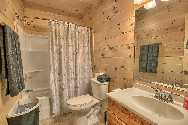 Full Bath 3, on Loft Level, Tub with Shower, Toilet, Sink and Mirror, Towel Rack and Clothes Hamper. Tile Floor.