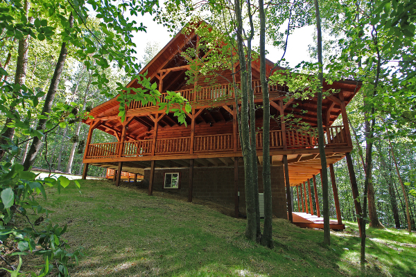 East Side of Lodge, showing Hillside and Trees, Walkout Back Porch, Main Level Wrap-Around Porch and additional Loft Level Covered Porch on this end.
