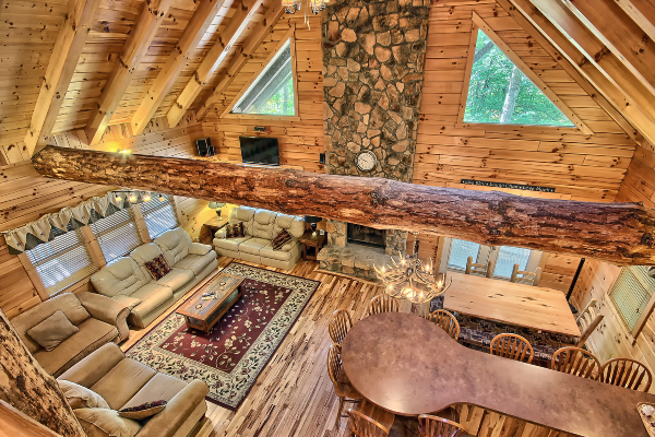 Great Room, Looking down from Open Loft, with big log beam and Fireplace, with large Triangular Windows on both sides. Great Room Couches and Loveseats, Dining Room Table and Chairs and extended Kitchen Counter, with 9 Chairs 