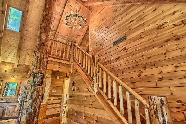 Another View of the welcome sign on vertical log post, Closeup of Stairway,to Upper Loft, with Log-Spindle Railing. Also up to Skylight over Kitchen. Also wall toward north hallway, with Fire Extenguisher