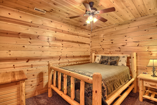 Private Bedroom 4, on Lower Level, with Queen Log Bed, Dresser and Nightstand with Lamp. Carpet Flooring.  Also, Ceiling Fan